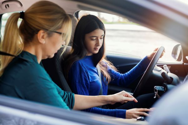 Instructor helping a teen driver in the car